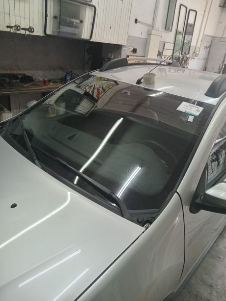 Un coche blanco visto desde el lado del pasajero delantero, mostrando el parabrisas.