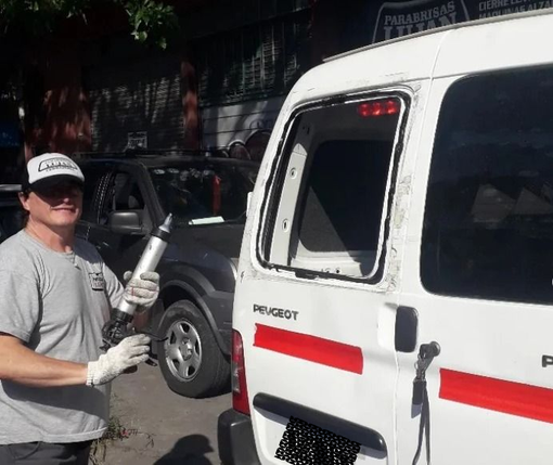 Un técnico, con guantes, sostiene una pistola de sellador mientras repara el marco de la ventana.
