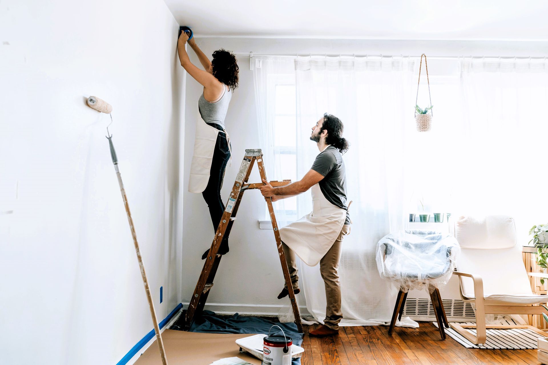Couple painting bright room during budget renovation