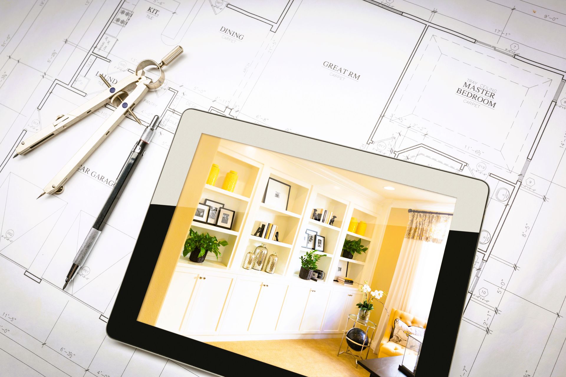 A tablet with home remodeling apps open, placed next to blueprints on a table.