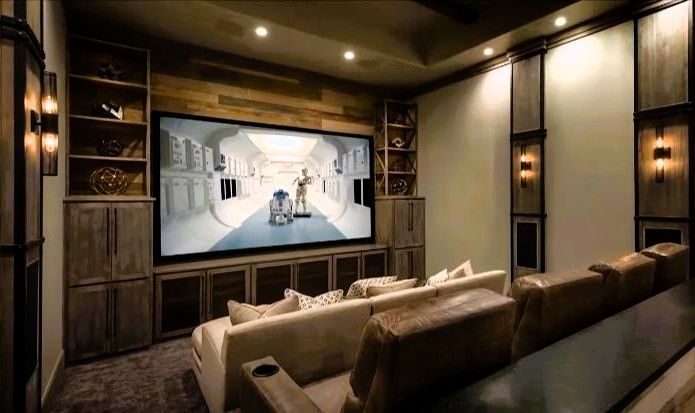 Luxury home theater room with large screen, recliner seating, and ambient lighting