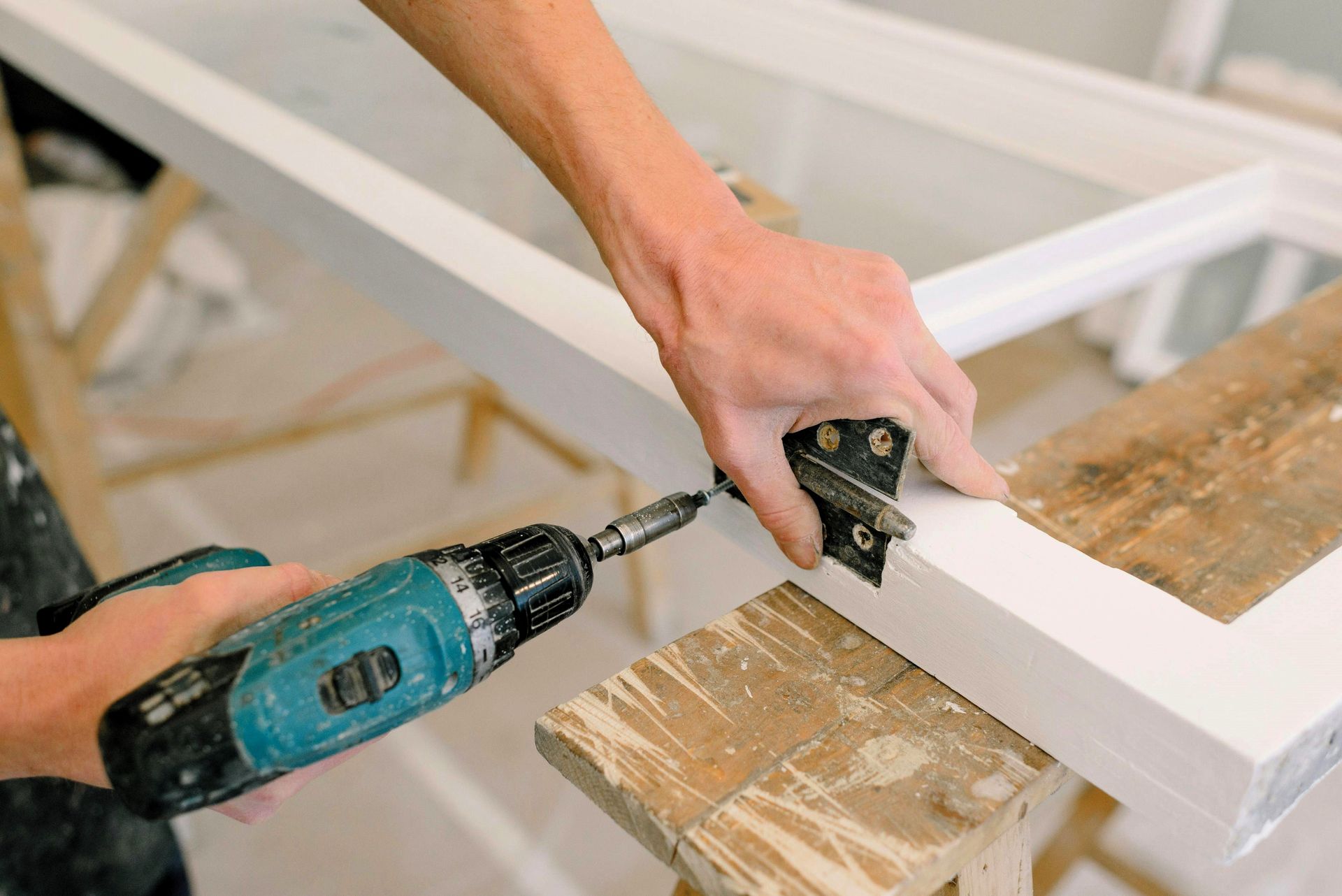 kitchen remodeling contractor using a cordless drill on a white wooden board during a home renovatio