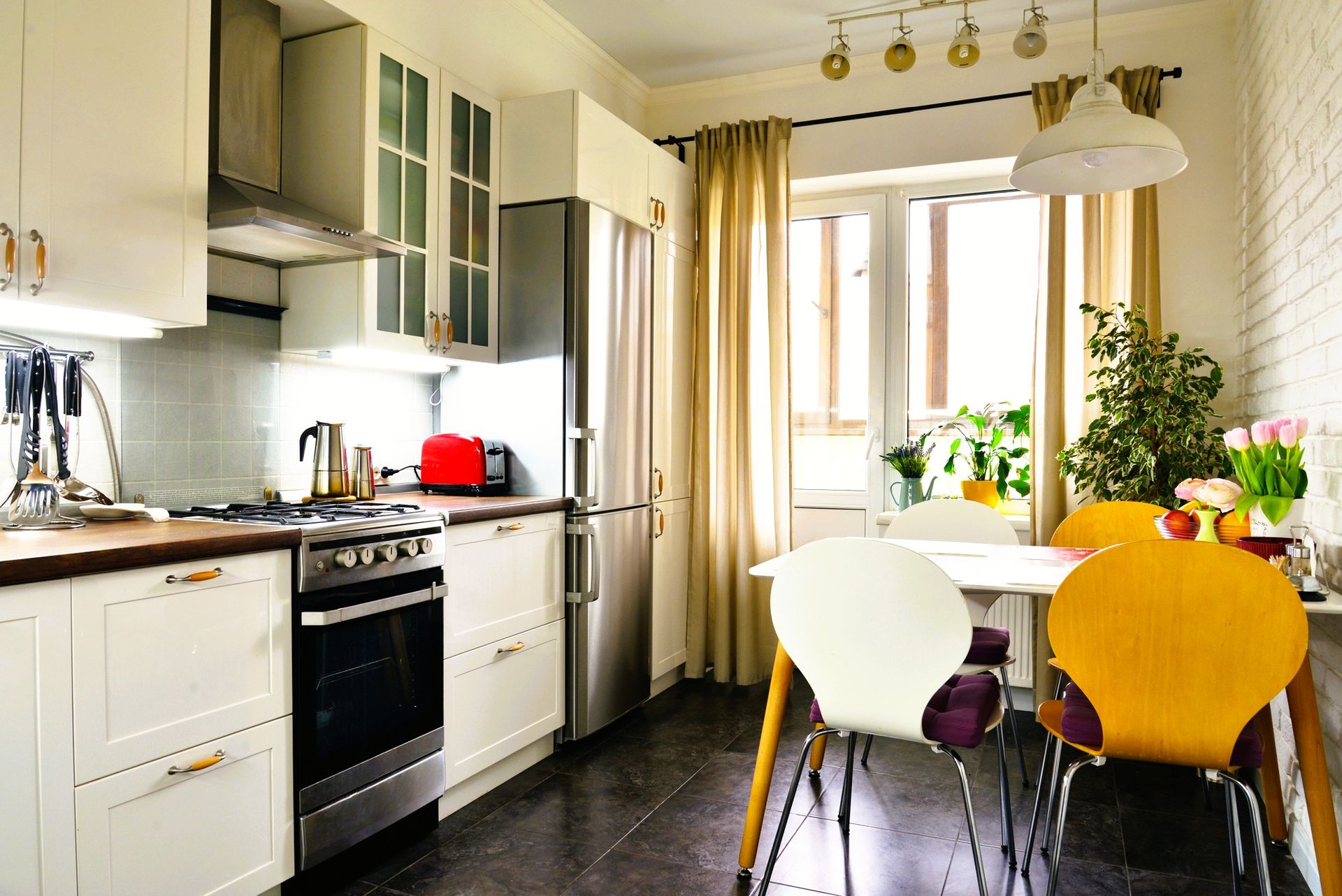Bright small kitchen with white cabinets, stainless steel appliances, and a wooden table