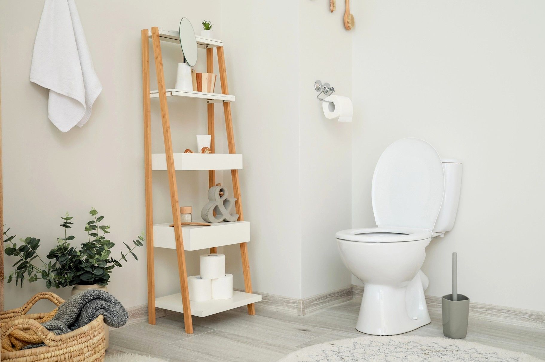 Small bathroom with ladder shelf storage, toilet, and woven basket for towels