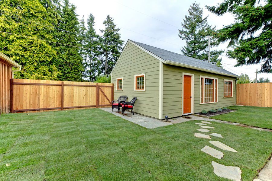 A small ADU (accessory dwelling unit) with a wooden fence in the backyard.