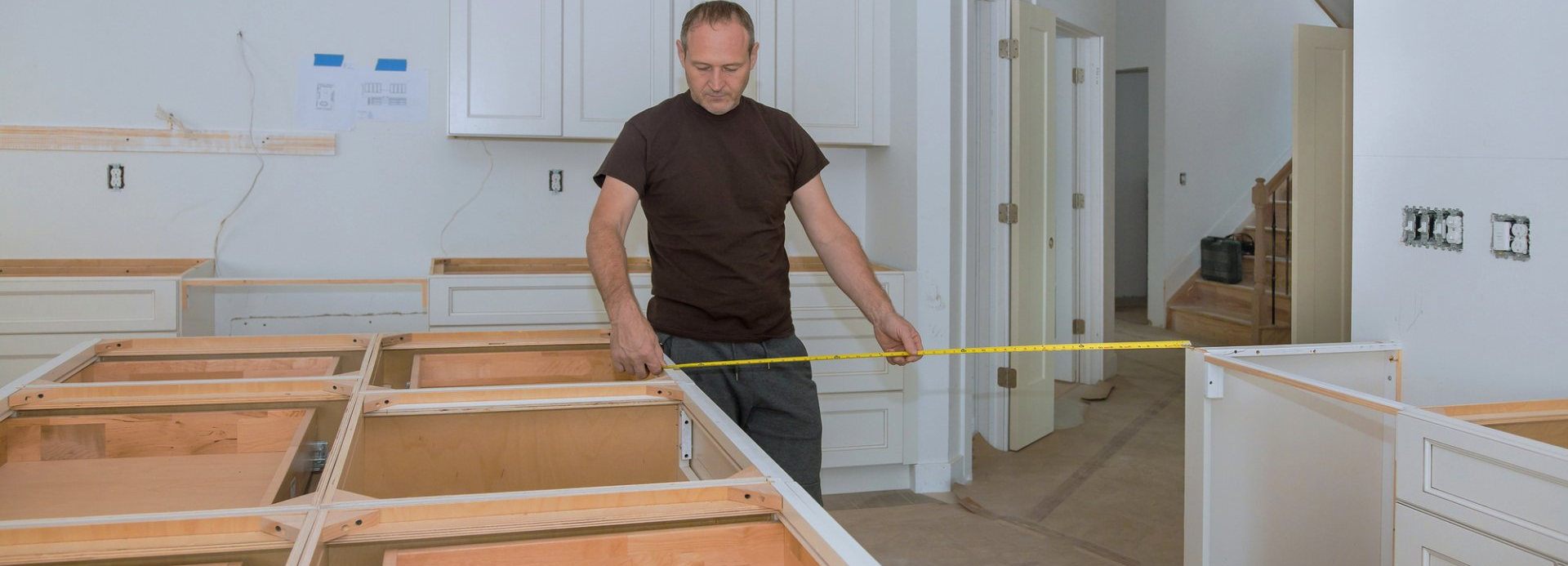 man measuring the space in the kitchen