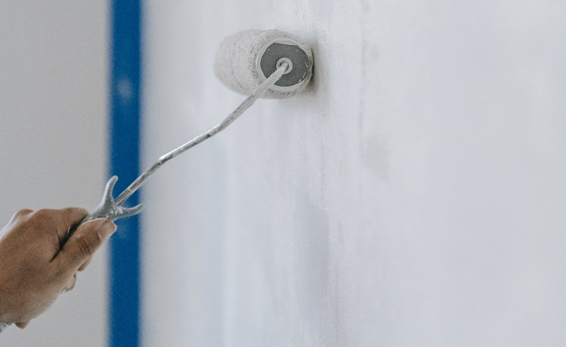 hand with paint roller painting a wall white