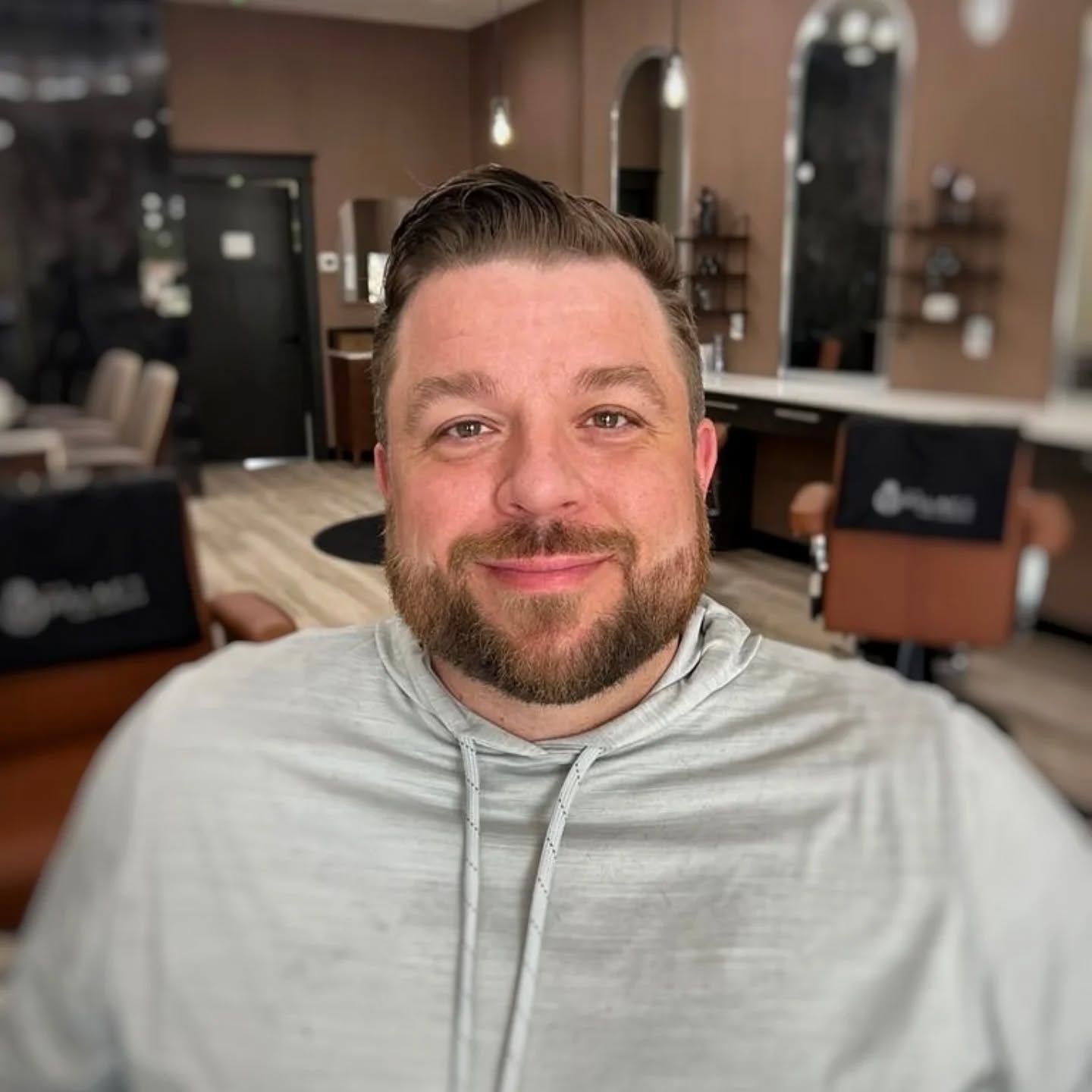 A man with a beard is sitting in a chair in a barber shop.