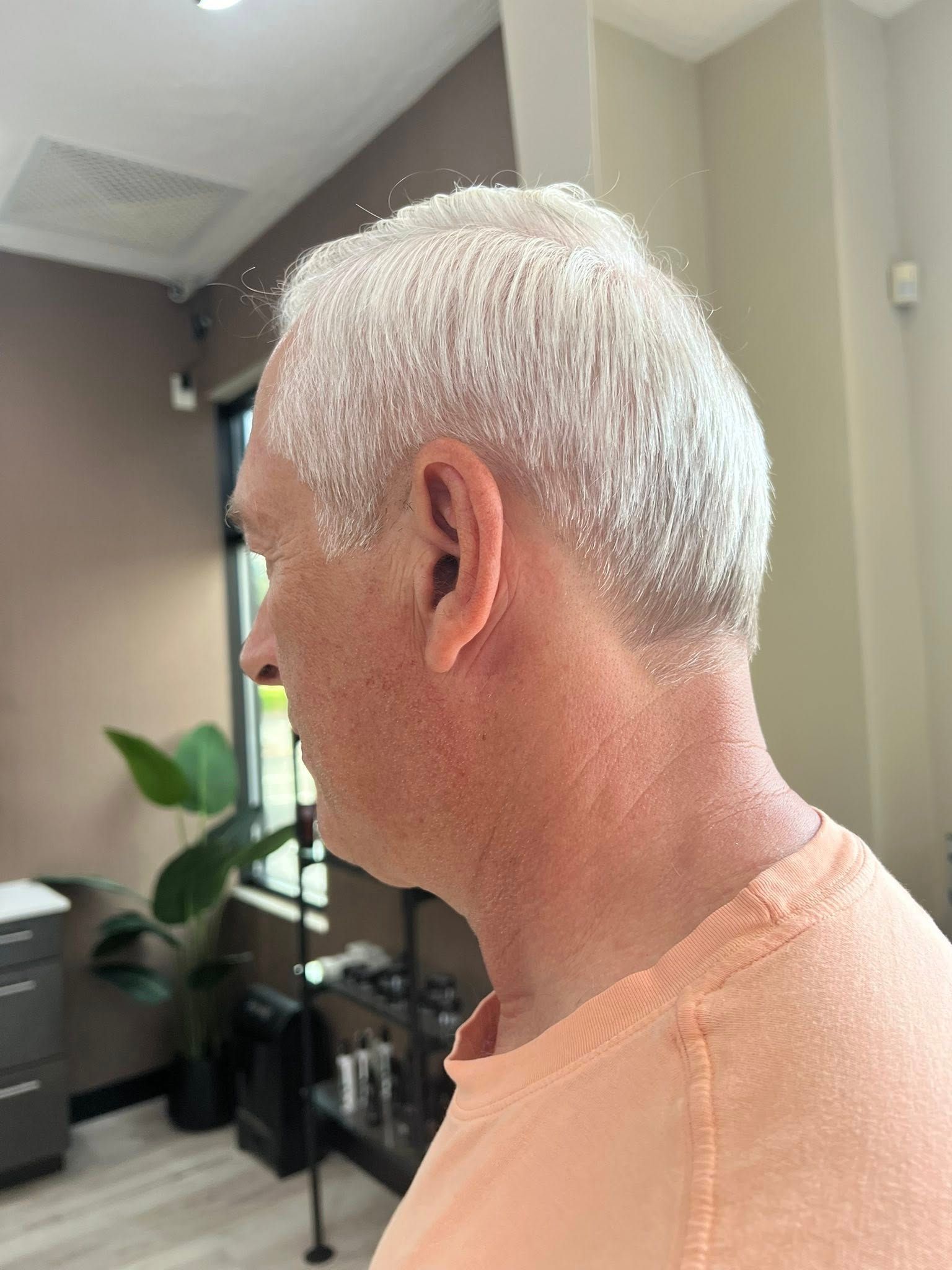 A man with white hair is standing in a room.