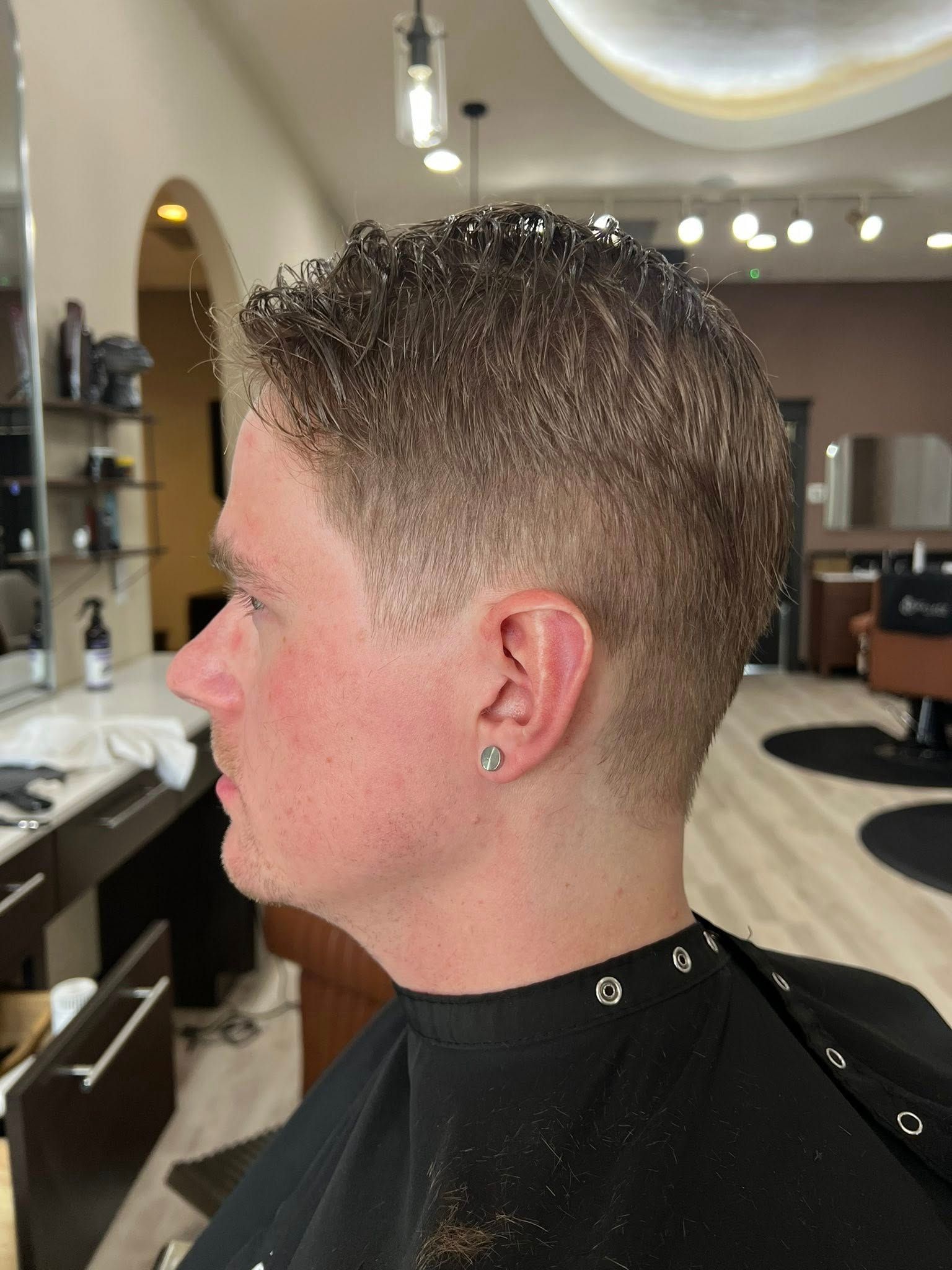 A man is getting his hair cut at a barber shop.