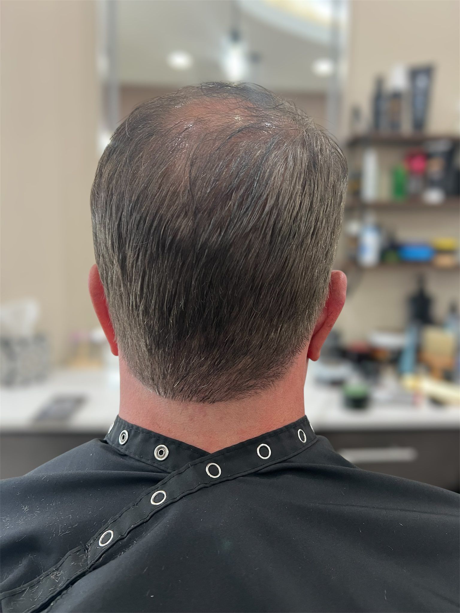 A man is getting his hair cut at a barber shop.