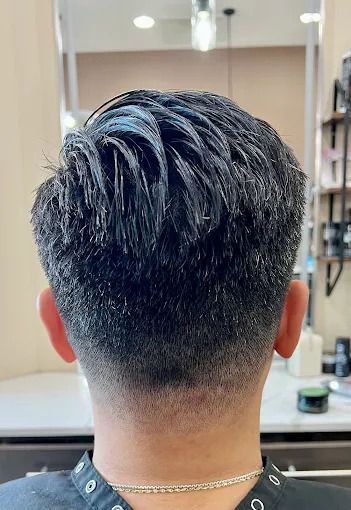 Close-up of the back of a person's head with a tapered haircut, styled with a wet look.