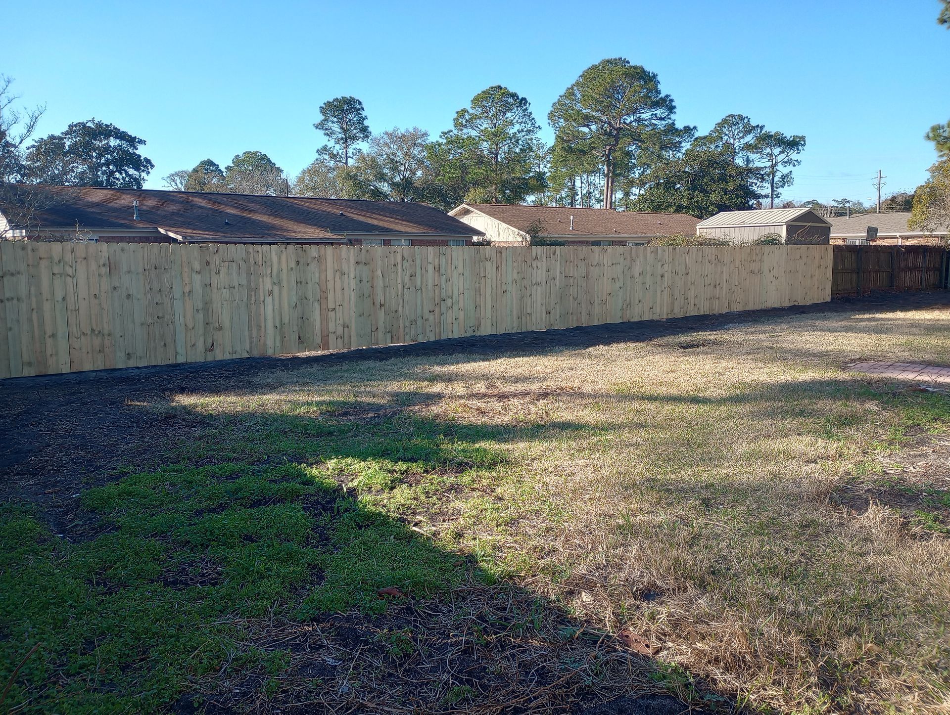 A Wooden Fence Is in The Middle of A Grassy Yard — Crestview, FL — Coastal View Fencing LLC