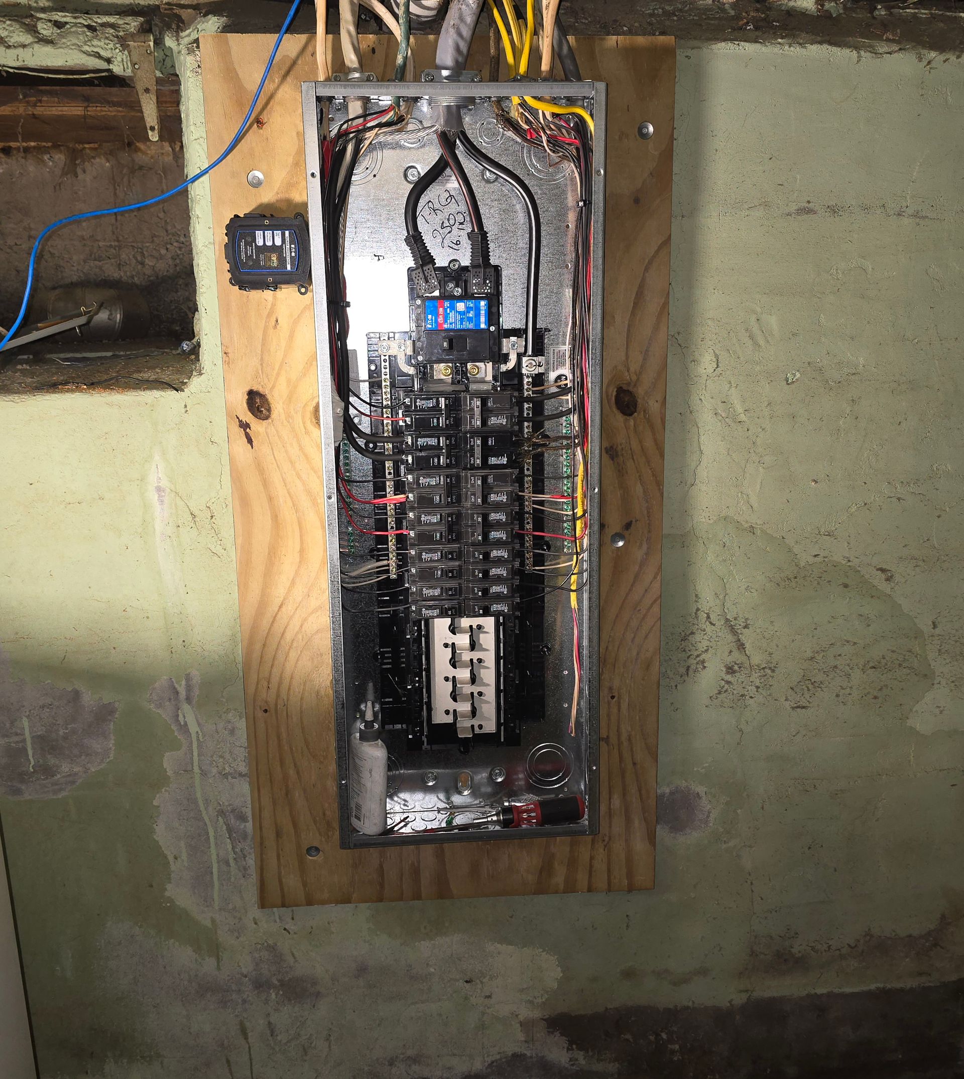 Electrical panel mounted on wood, with visible breakers and wiring.