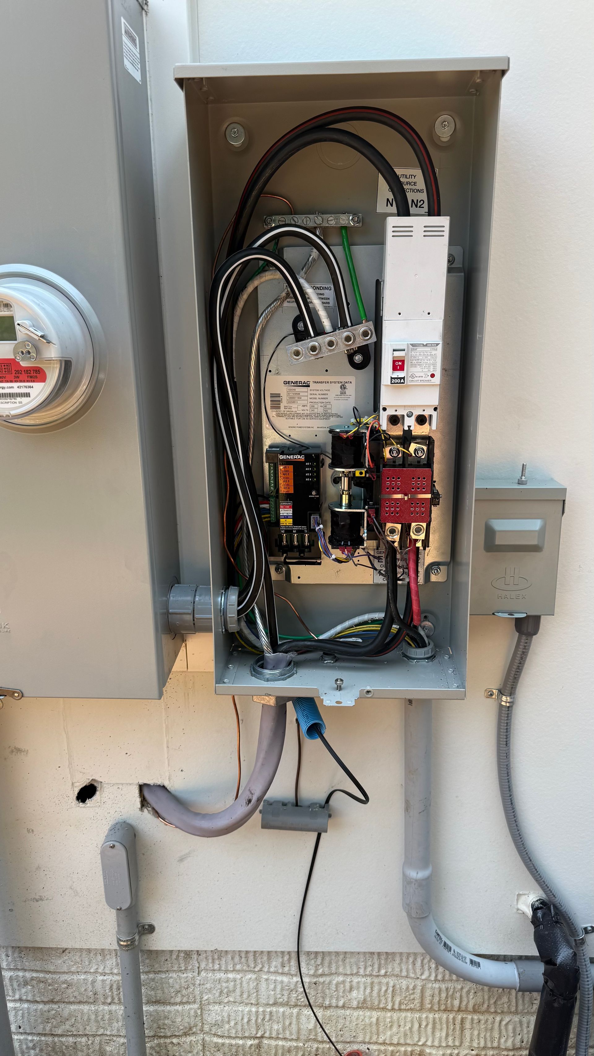 Electrical panel on an exterior wall with wires and components visible.