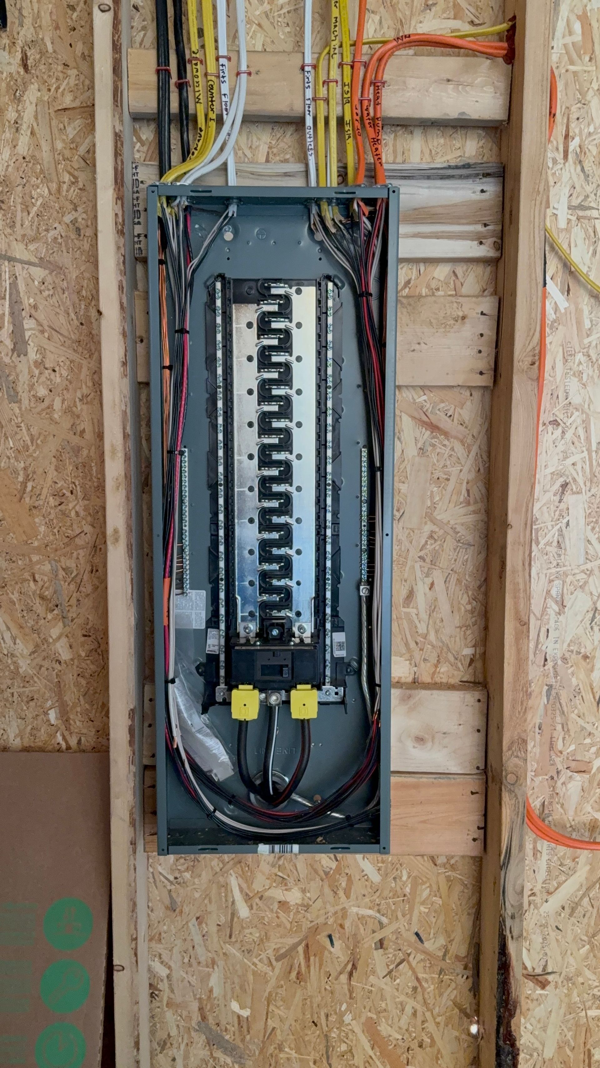 Electrical panel installed on a wooden wall, with various colored wires entering.