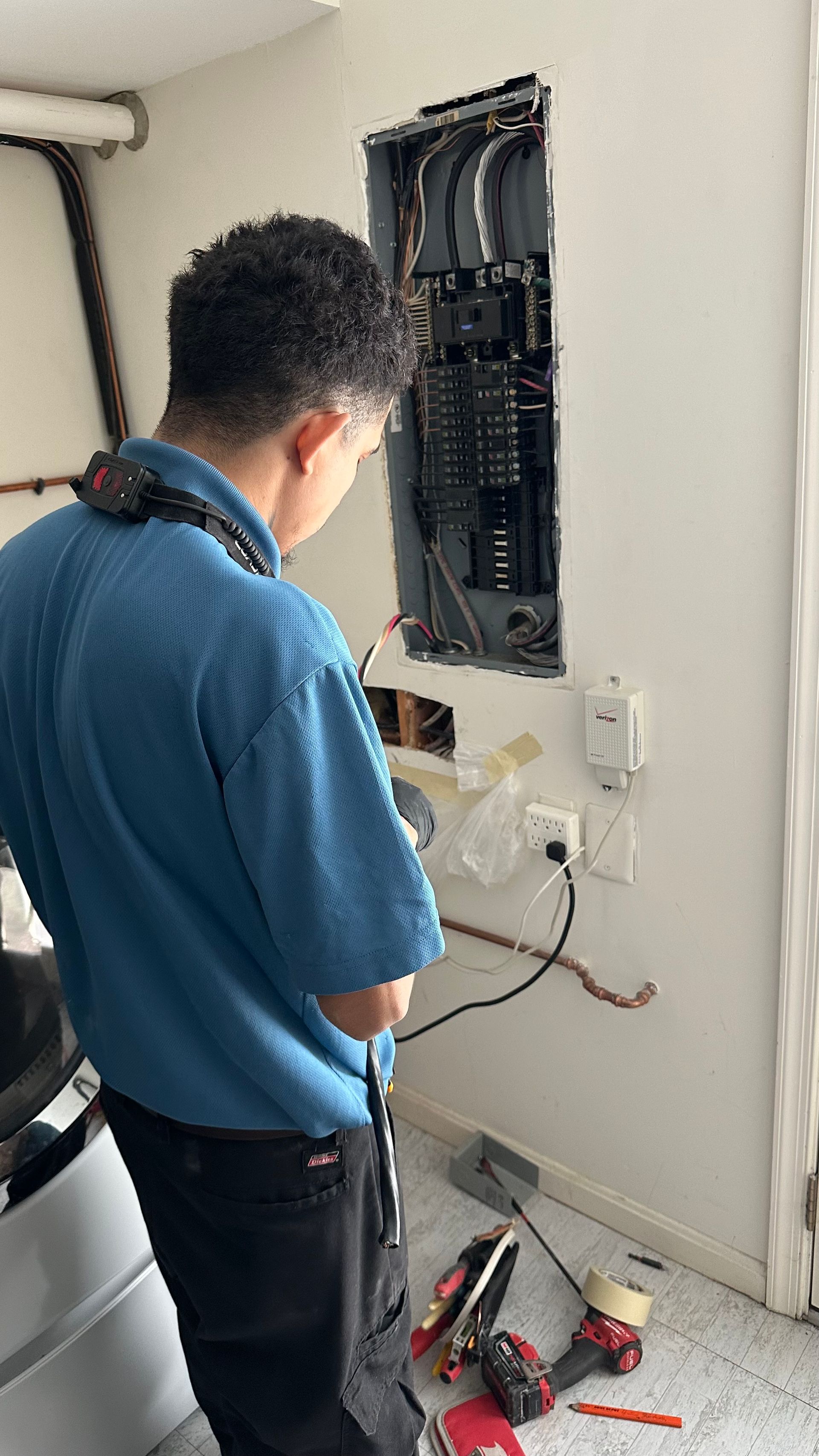 Electrician working on an electrical panel inside a building.