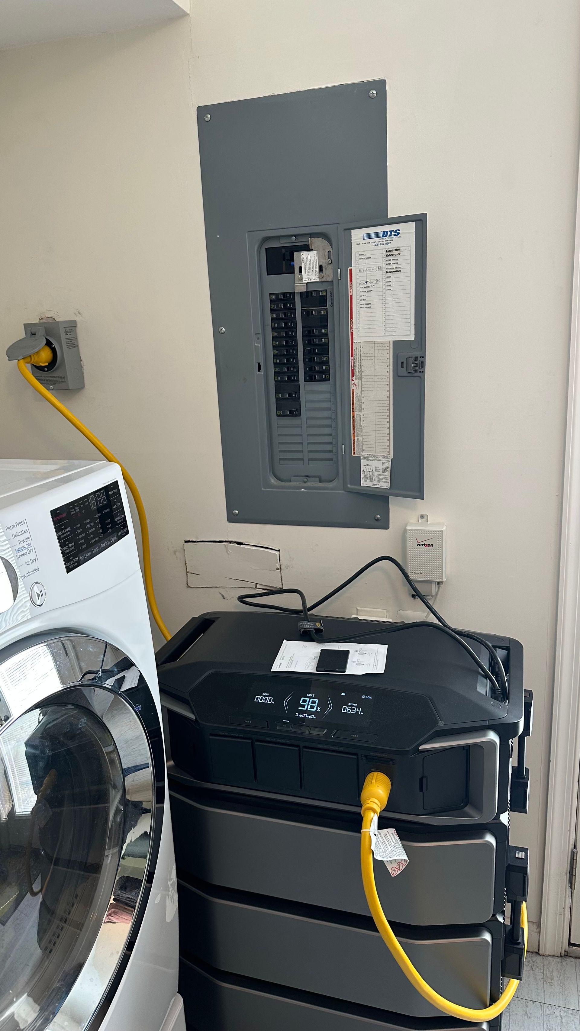Electrical panel and a battery storage system in a utility room with a washing machine.