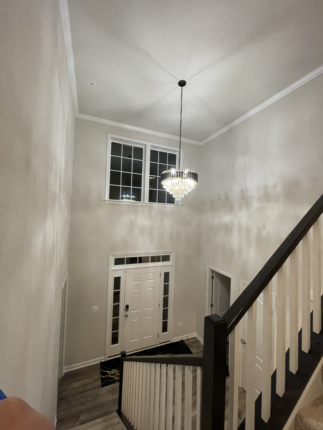 Entryway with stairs, front door, and chandelier hanging from the high ceiling.