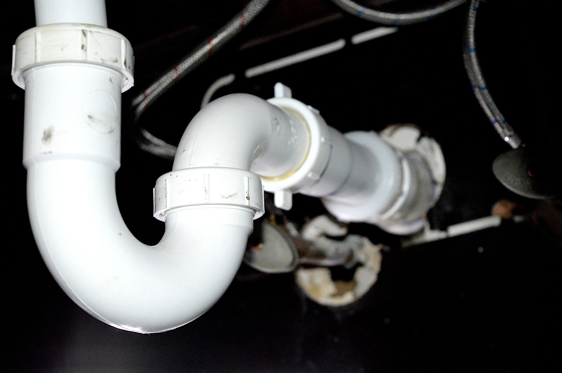 A close up of a white pipe under a sink.