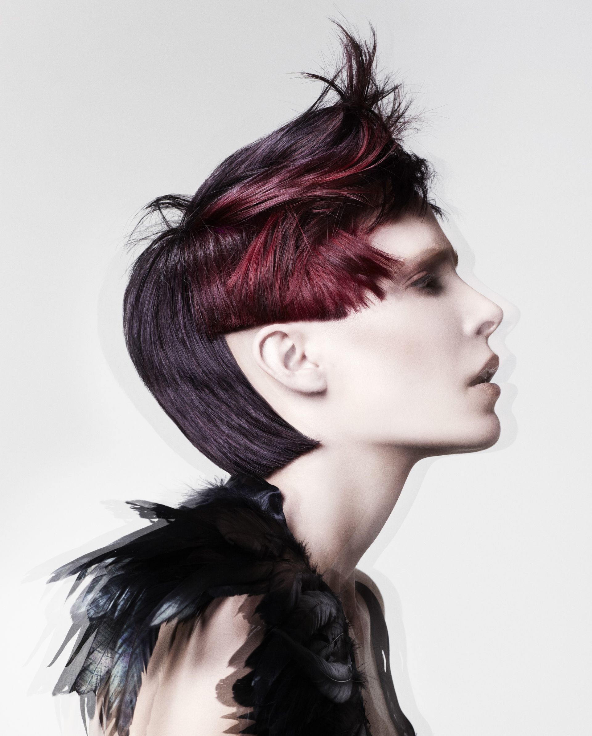 Two models with edgy hairstyles and dramatic makeup. One has blonde hair with orange and yellow streaks; the other has white hair with a blue streak.