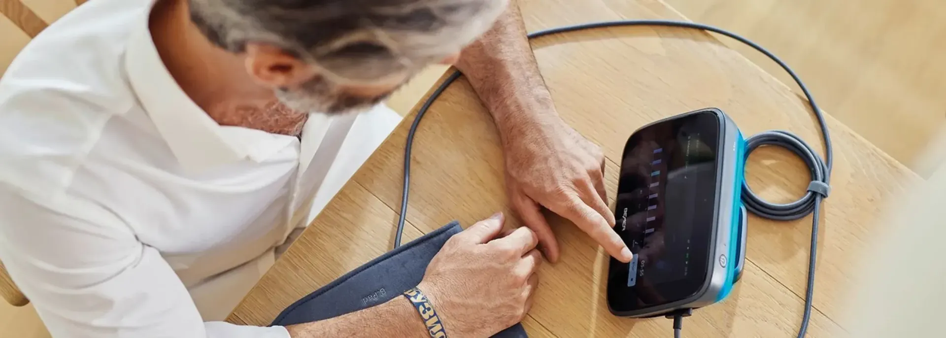 A person uses a charging station with a screen and blue trim on a wooden surface.