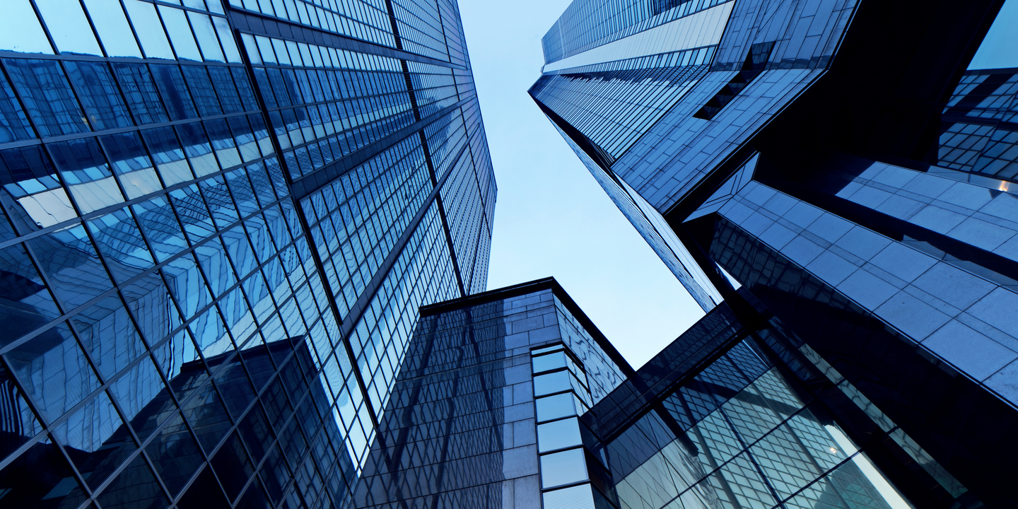 Looking up at a group of tall buildings with a blue sky in the background.