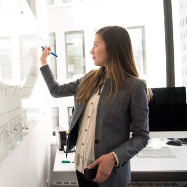 A woman is writing on a whiteboard with a pen.