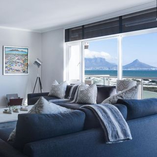 A living room with a blue couch and a view of the ocean