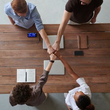 A group of people putting their hands together on a wooden table