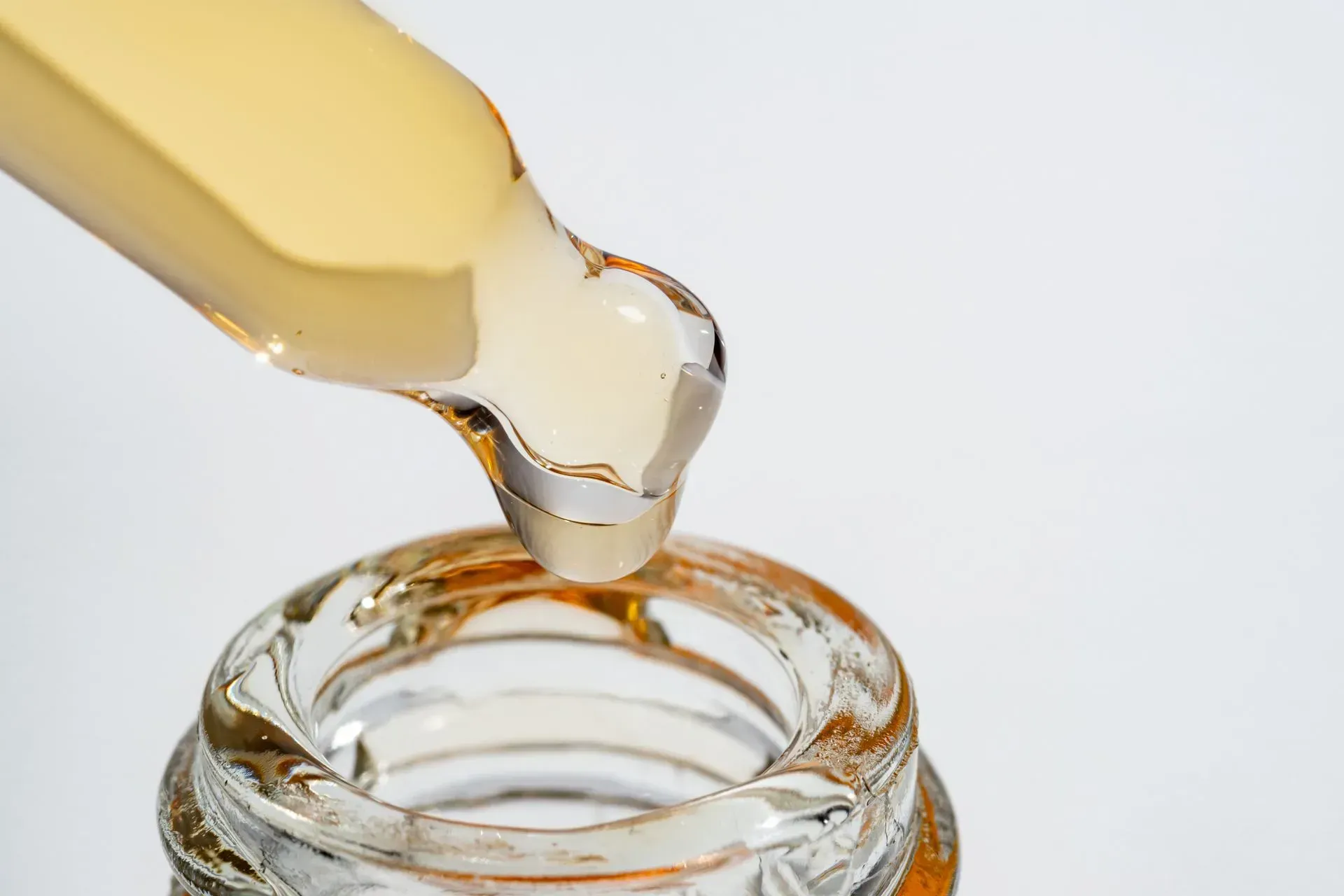 Dropper releasing yellow liquid into glass jar