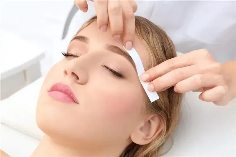 Facial treatment with hands applying pads to a woman’s closed eyes in a spa setting