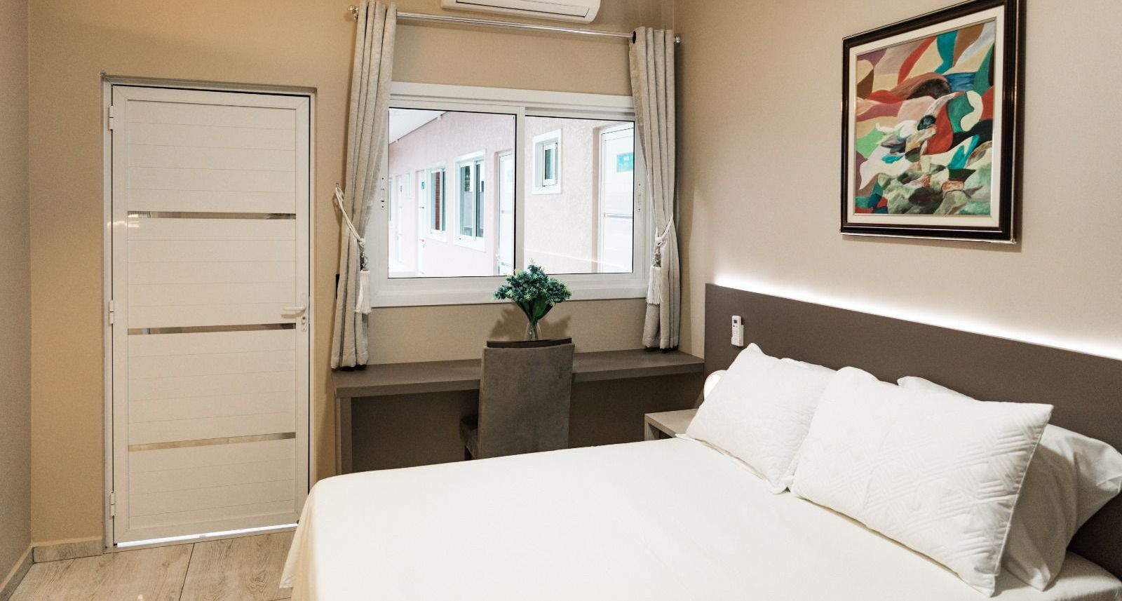 Um quarto com uma cama, escrivaninha e janela. MD Recanto Hotel