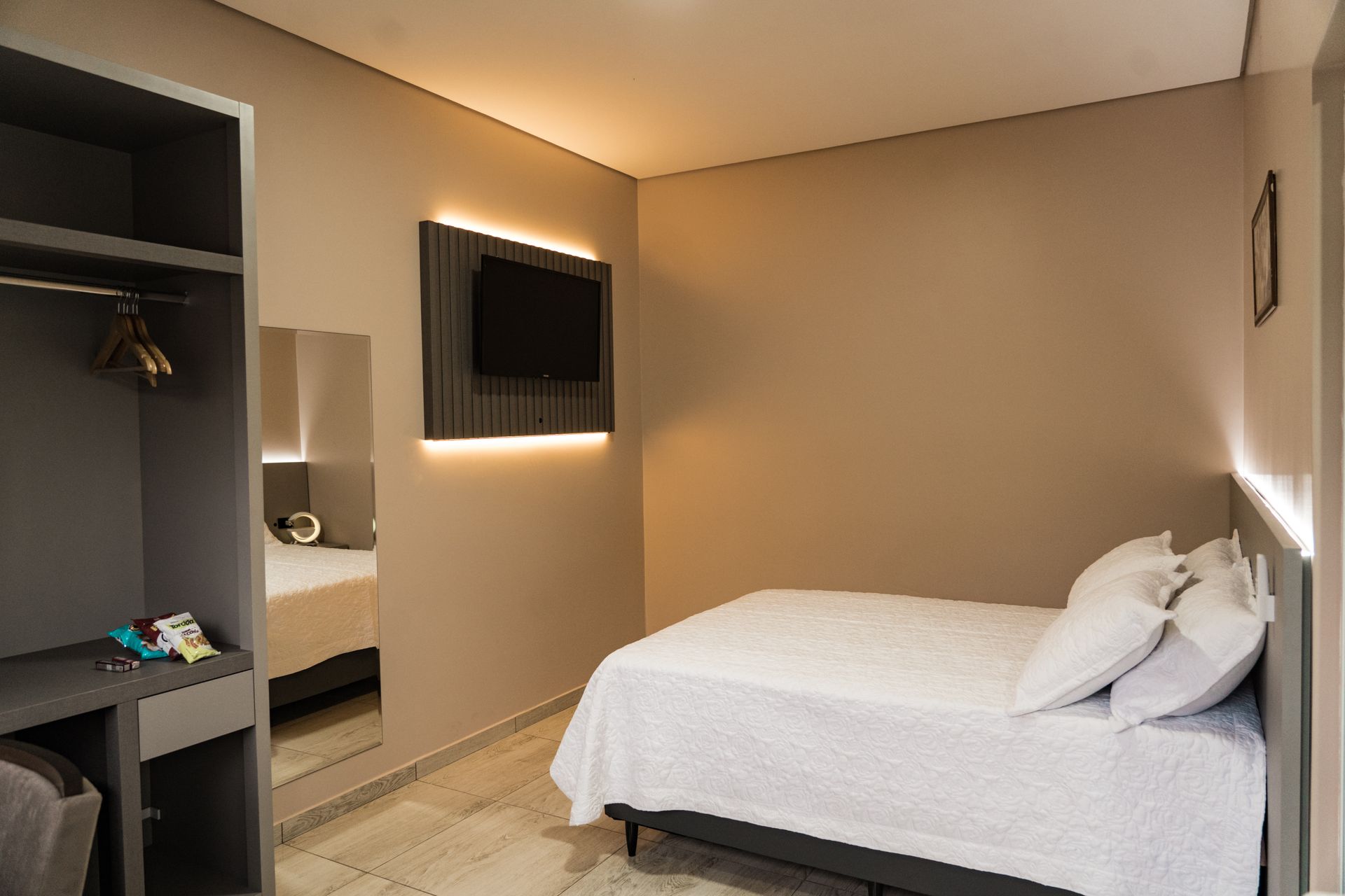 Um quarto de hotel com uma cama de solteiro e uma TV de tela plana. MD Recanto Hotel