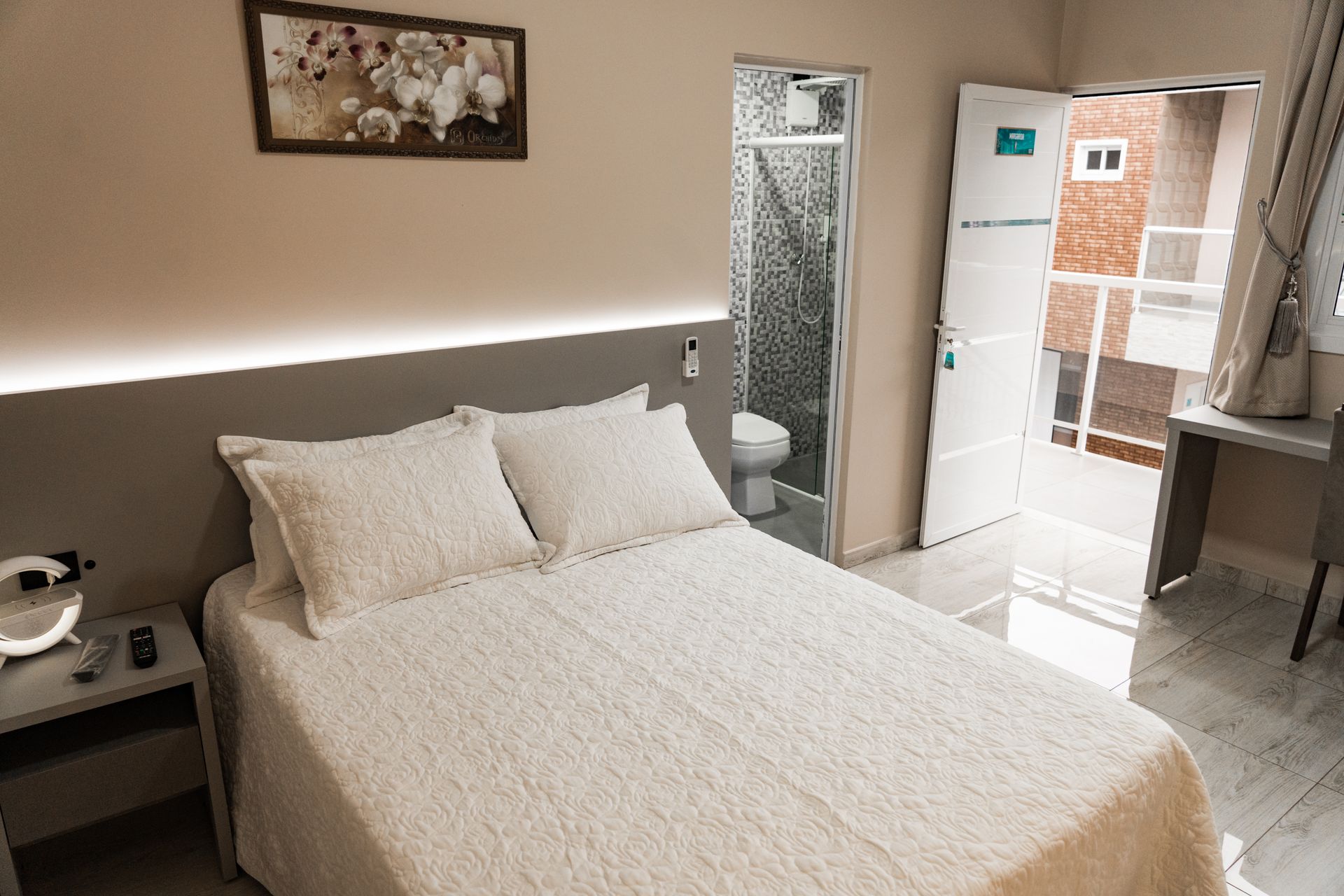 Um quarto com cama, mesa de cabeceira, geladeira e banheiro. MD Recanto Hotel