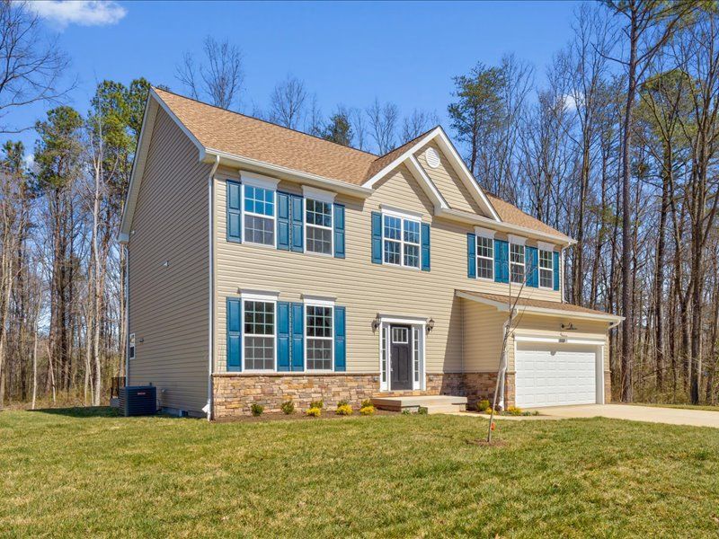 A large house with blue shutters is surrounded by trees and grass.