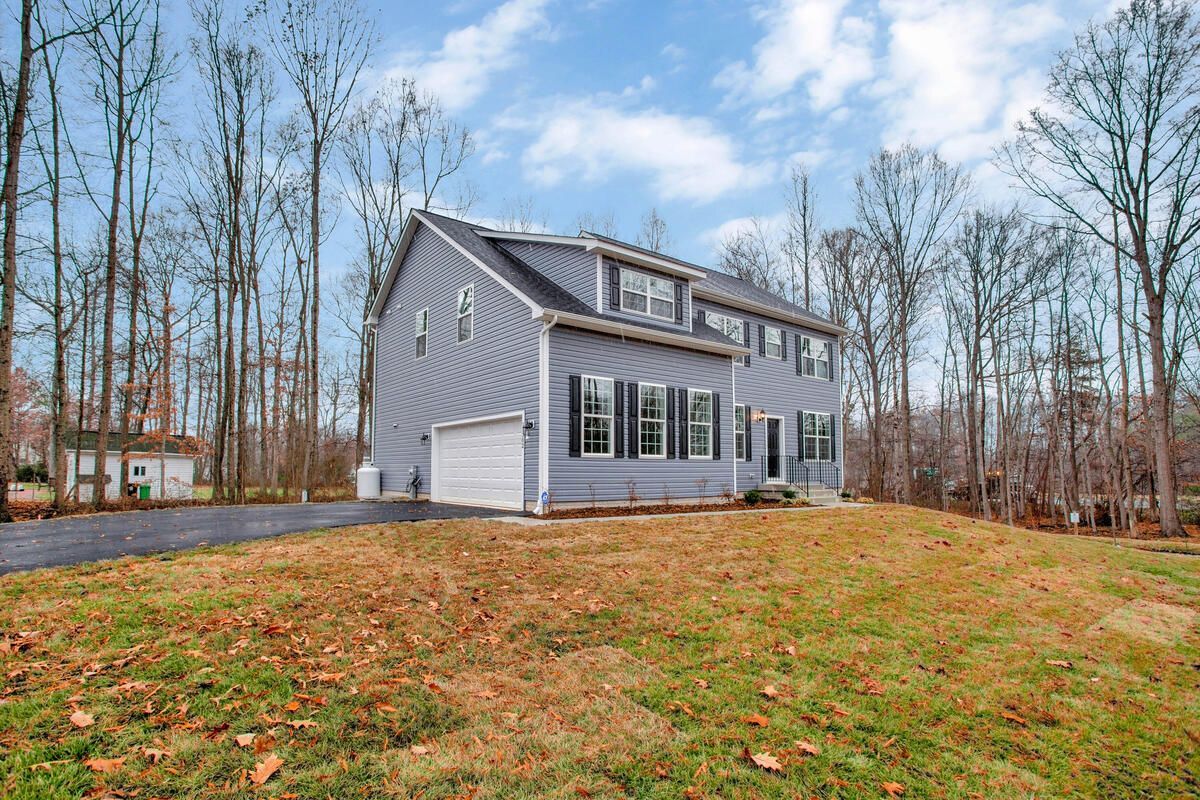 A large house is sitting on top of a lush green field surrounded by trees.