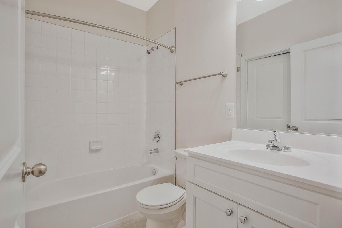 A bathroom with a toilet , sink , bathtub and mirror.