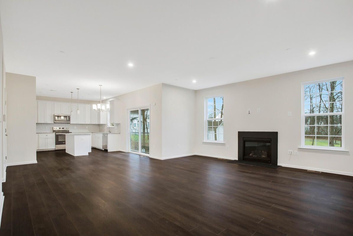 An empty living room with hardwood floors and a fireplace in a new home.