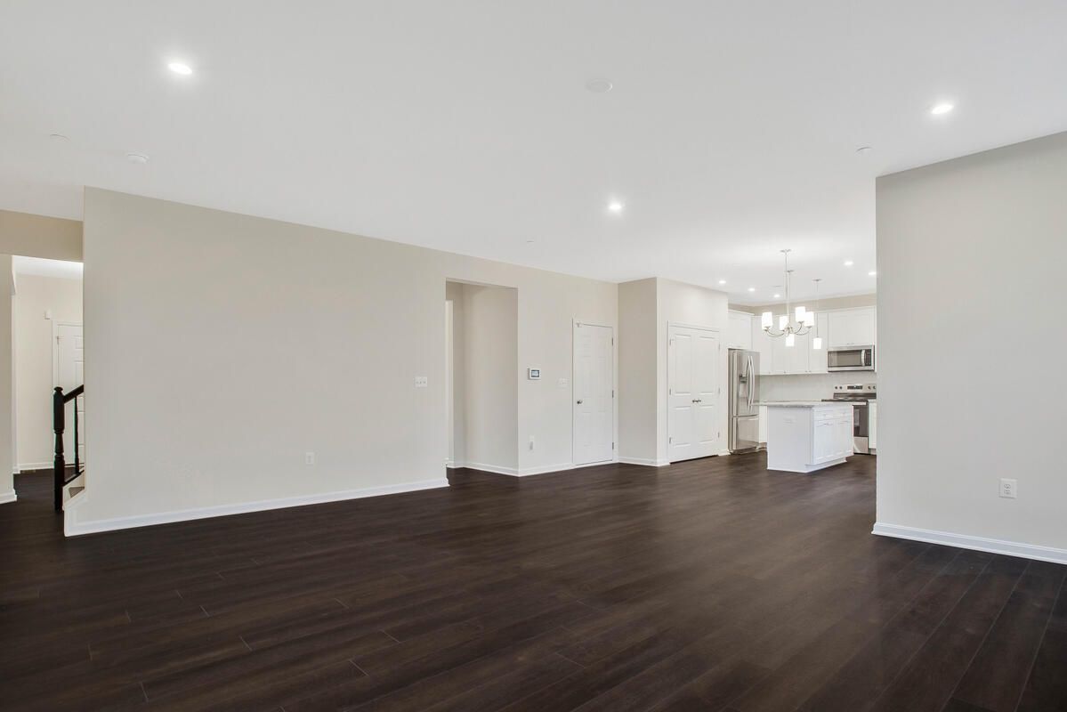 An empty living room with hardwood floors and white walls.