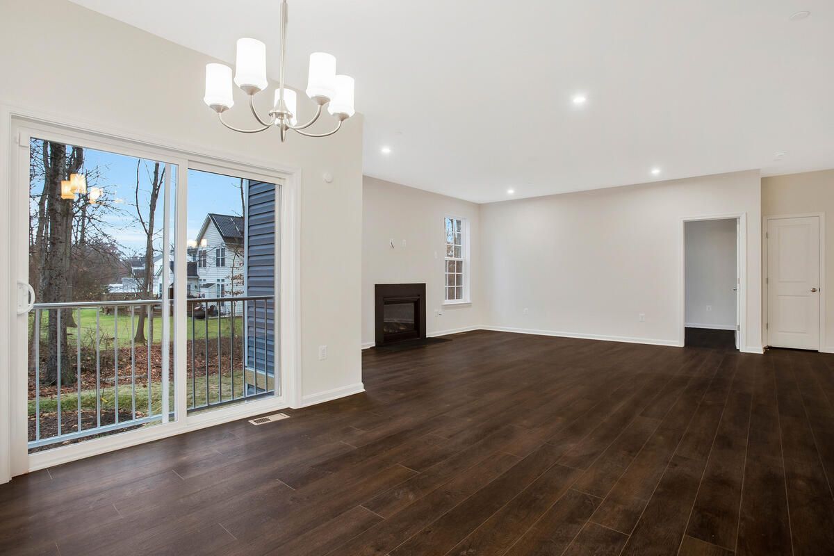 An empty living room with a fireplace and sliding glass doors.