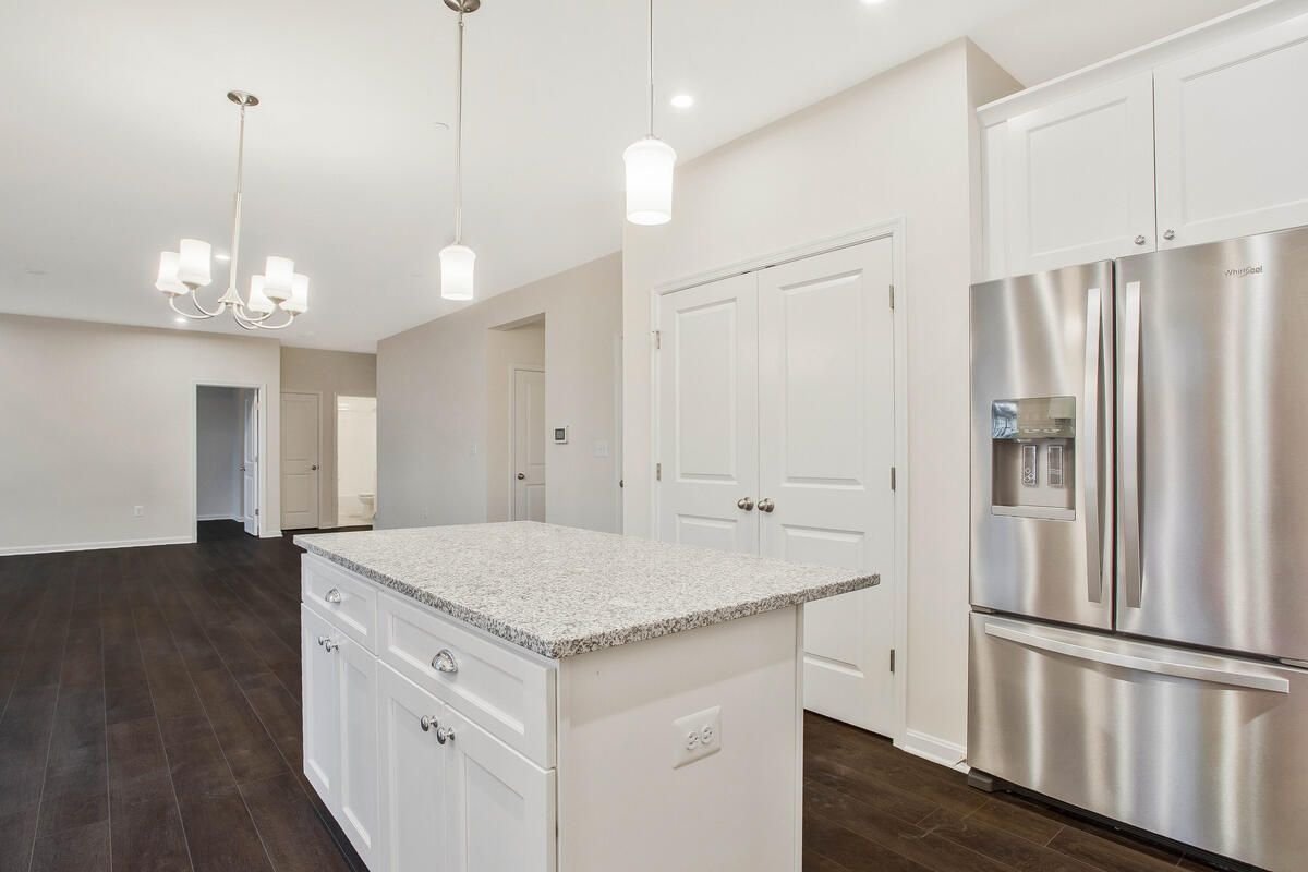 A kitchen with a large island and a stainless steel refrigerator.