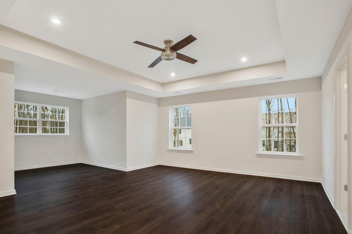 An empty room with a ceiling fan and two windows