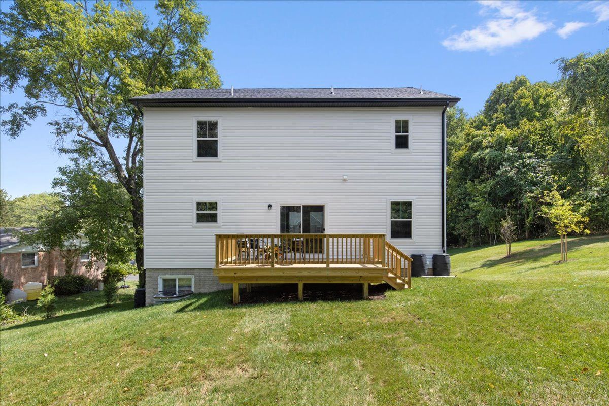 The back of a white house with a wooden deck.
