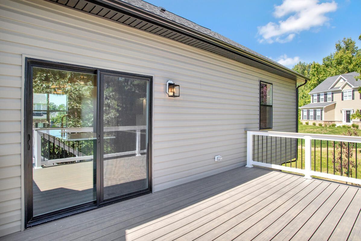 There is a deck with a sliding glass door on the side of the house.