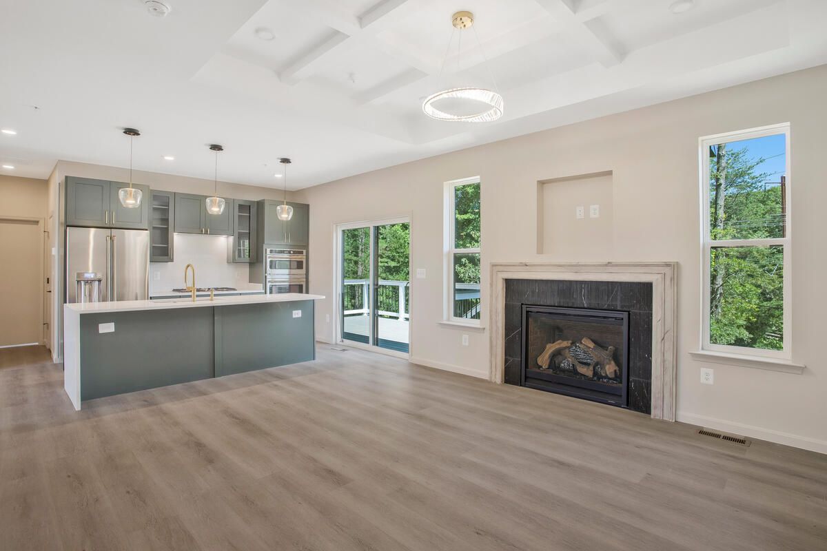 A living room with a fireplace and a kitchen in the background.
