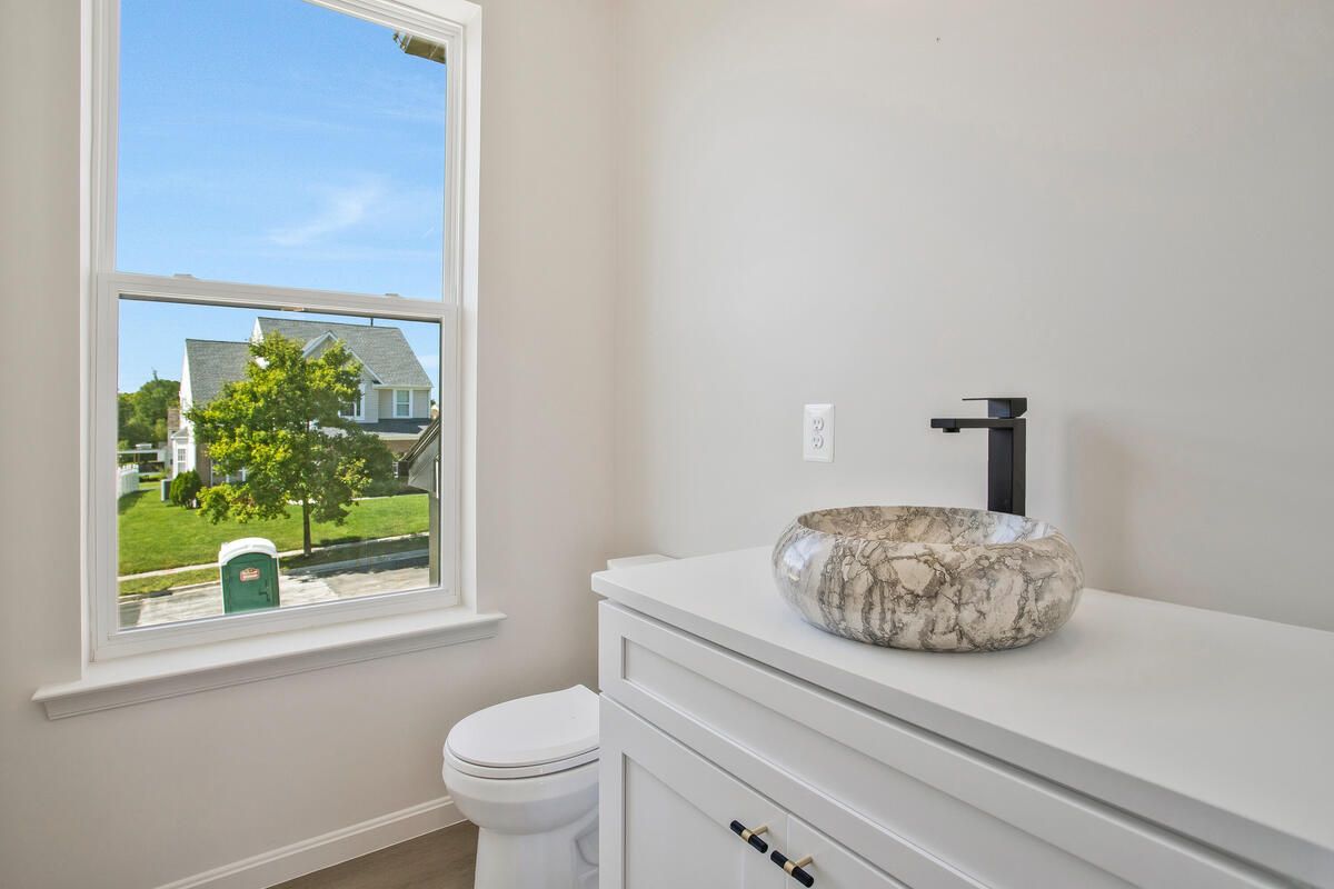 A bathroom with a toilet , sink and window.