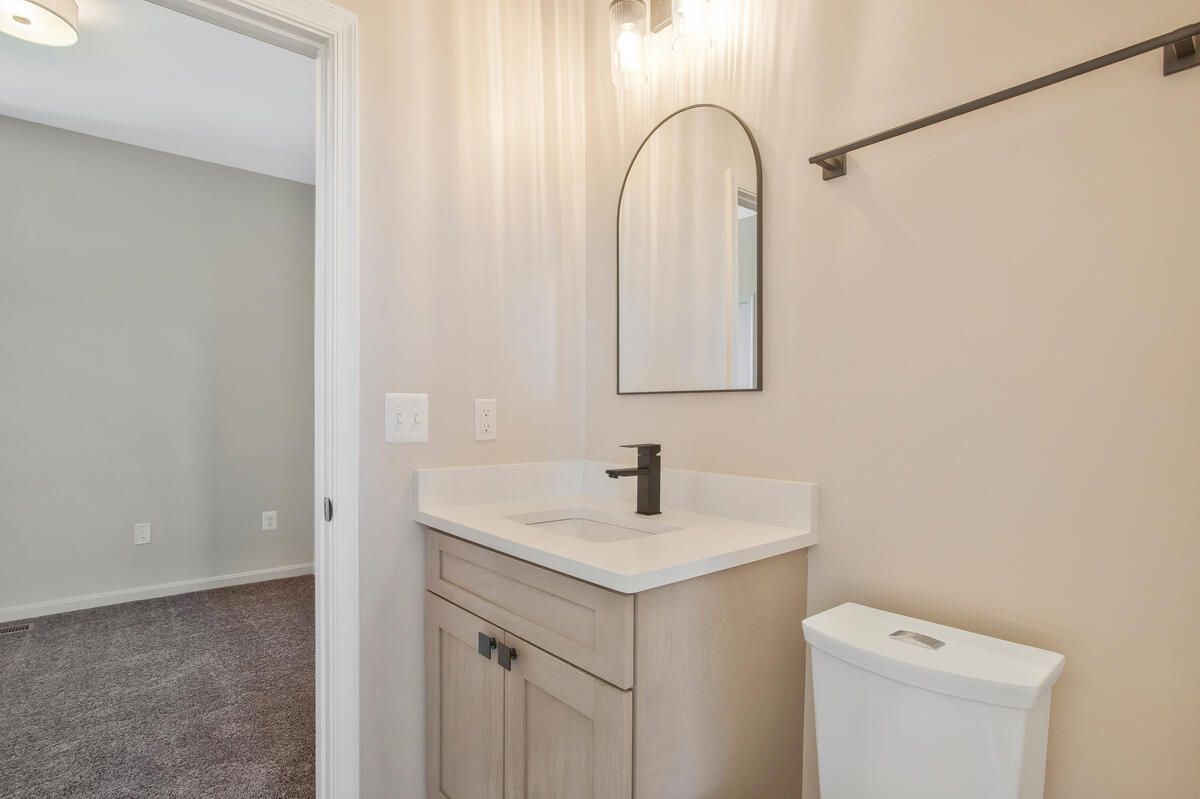 A bathroom with a sink , toilet and mirror.