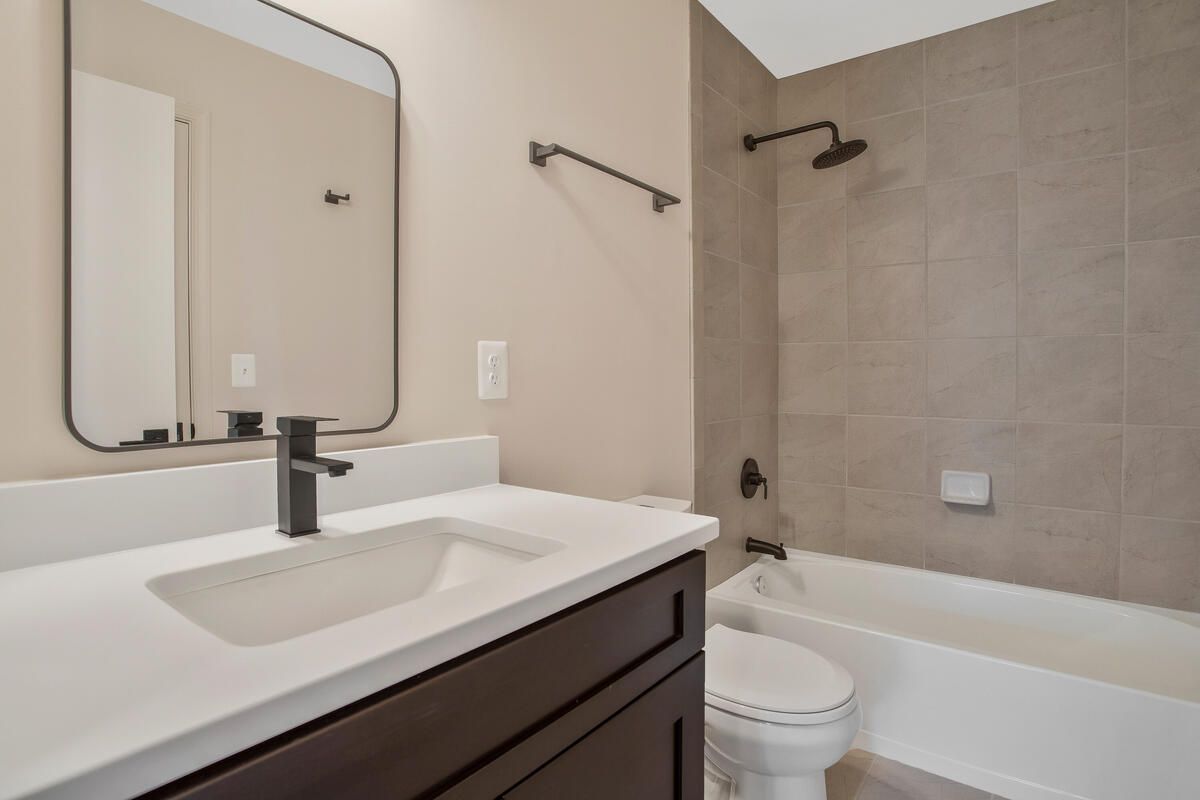 A bathroom with a sink , toilet , bathtub and mirror.