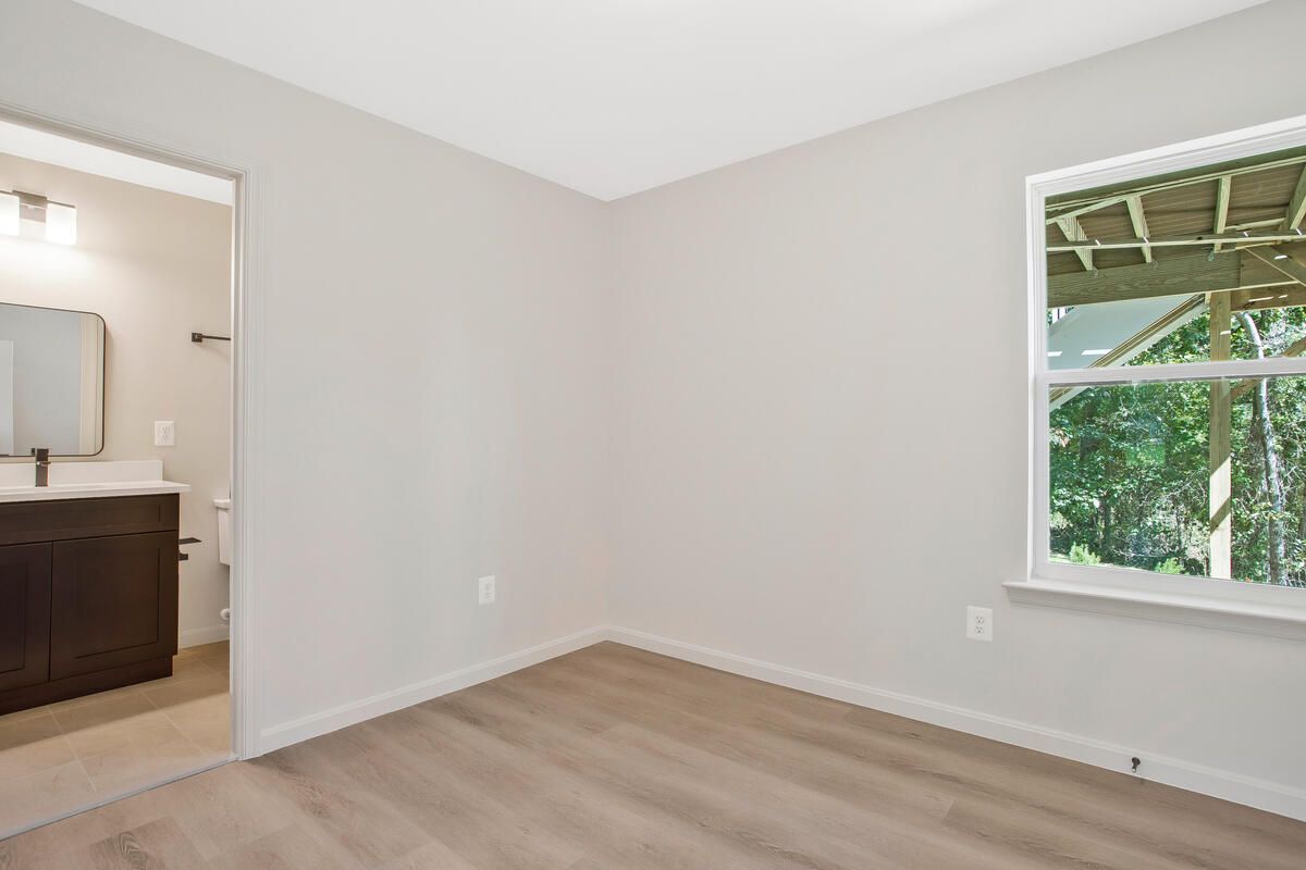 An empty room with a window and a bathroom in the background.